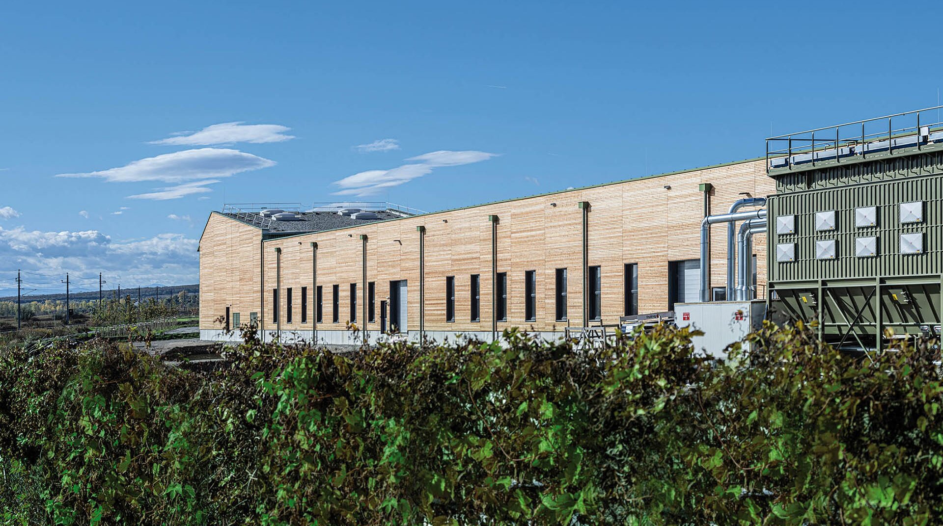 Die Austrotherm Fabrik, welche 2023 zur Green Factory des Jahres gekürt wurde. Hier in der Außenansicht mit Holzverkleidung im Grünen.