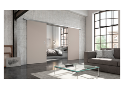 Industriell inspiriertes Wohnzimmer mit großen Fenstern, grauem Sofa und beigen Schiebetüren, die ein Schlafzimmer offenbaren