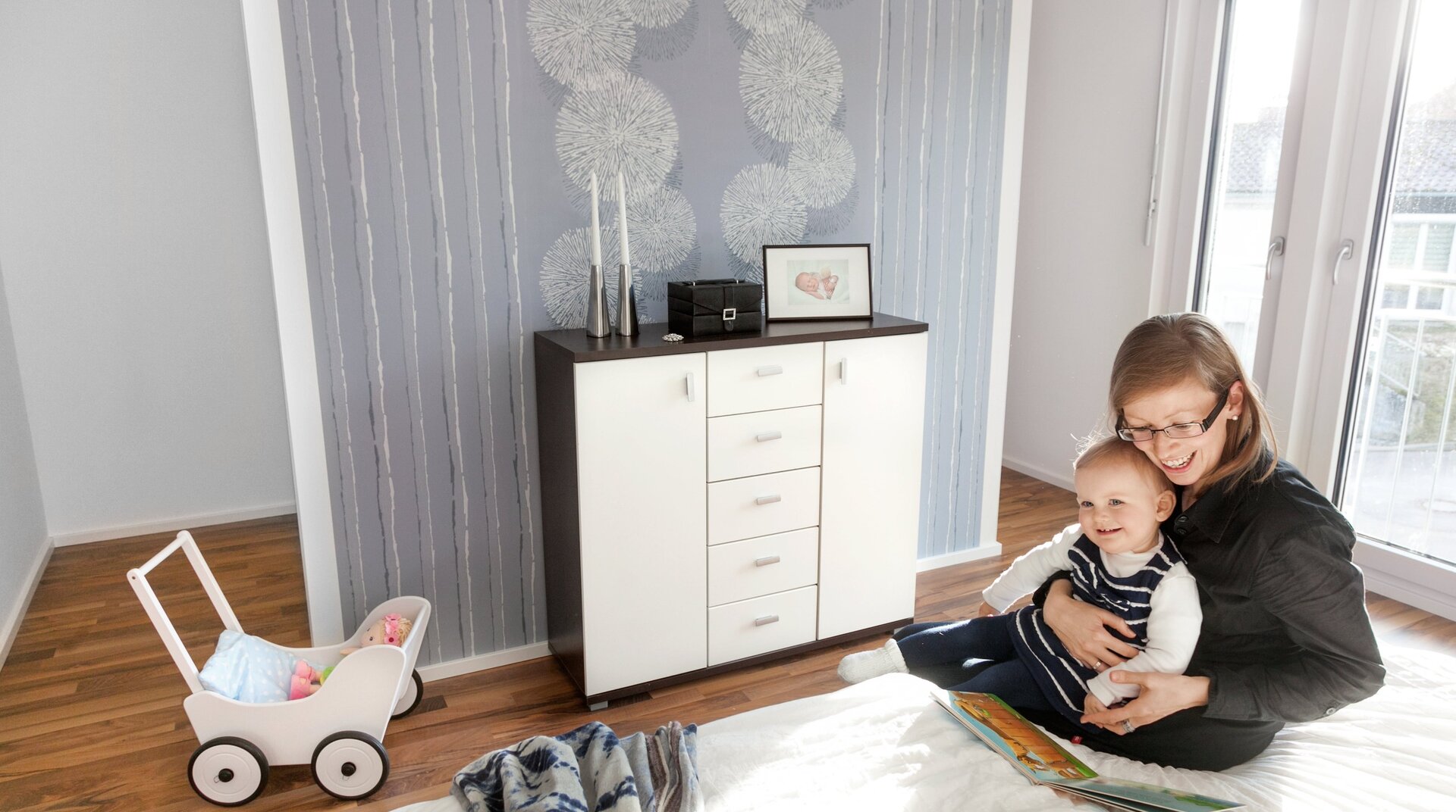 SchwörerHaus Willbord Ehringen, Schlafzimmer, Mutter und Baby sitzend auf Bett